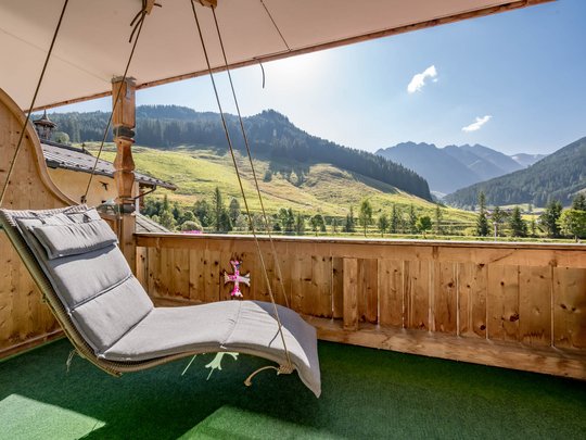 Rooms & suites in Gerlos • Der Grubacher: Eco Hotel in Tyrol Hanging swing on a balcony with mountain view in summer