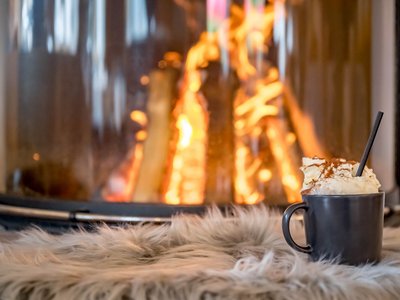 Der Grubacher • Unter den Biohotels in Tirol die beste Wahl Kakao mit Schlagsahne vor einem brennenden Kachelofen