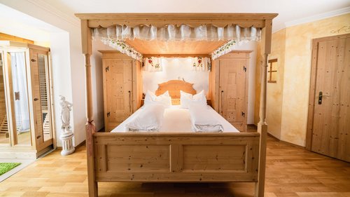 Our water world in Gerlos • Der Grubacher: Eco Hotel in Tyrol Canopy bed in a hotel room with parquet floor and carpet
