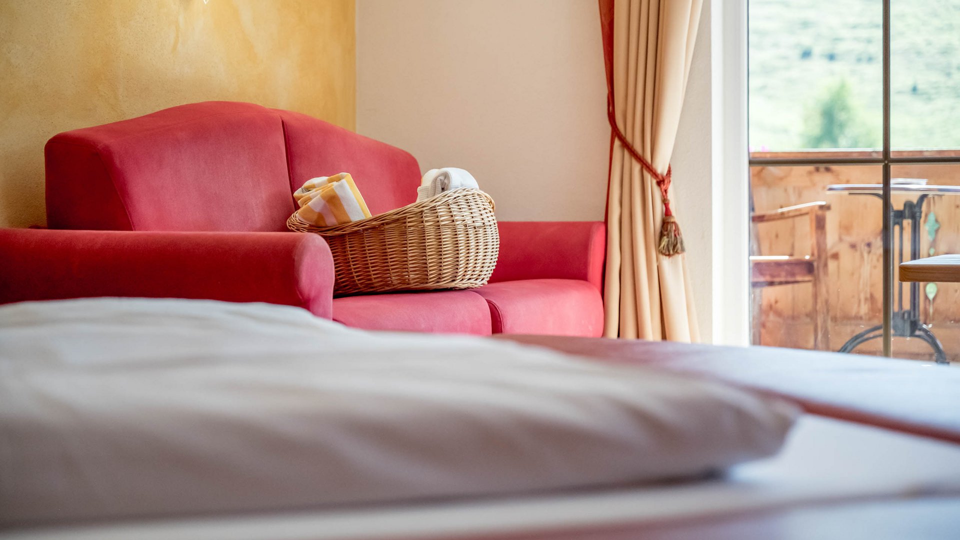 Rooms & suites in Gerlos • Der Grubacher: Eco Hotel in Tyrol Hotel room with bed, sofa, wellness bag, and balcony