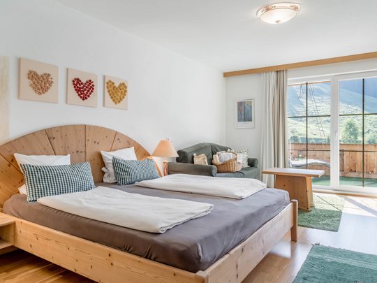 Rooms & suites in Gerlos • Der Grubacher: Eco Hotel in Tyrol Hotel room with double bed, pictures made of dried flowers, and balcony