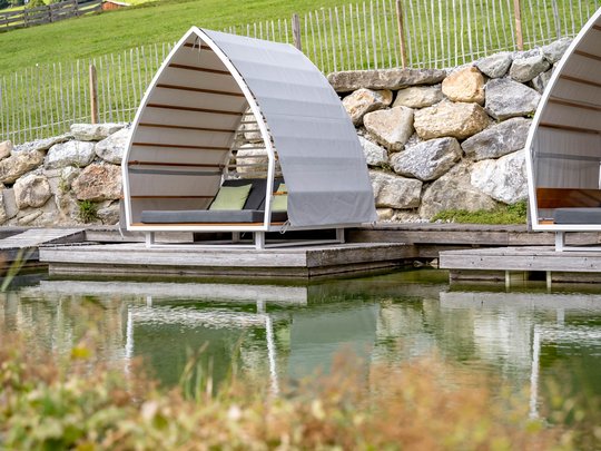 Our water world in Gerlos • Der Grubacher: Eco Hotel in Tyrol Garden loungers by the swimming pond with a view of the meadow